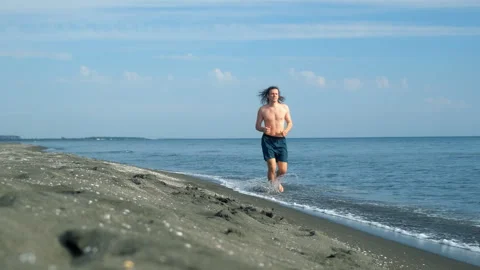 Long-haired man running barefoot on sea sandy beach on vacations. Stock-Footage 311466910
