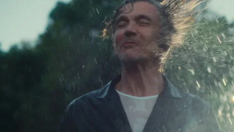 Long haired man standing in the heavy summer rain Stock Footage 279060639