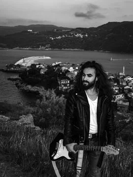 Long haired man walking around with his guitar Stock Photos