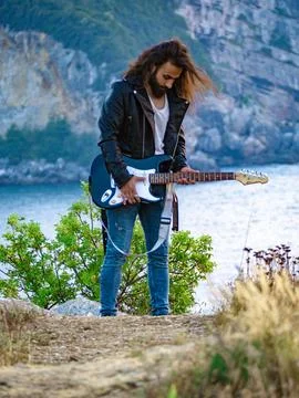 Long haired man walking around with his guitar Stock Photos