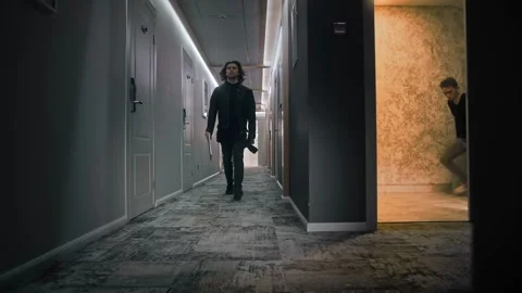 A long-haired man is walking down the corridor of a hotel floor. He is dressed Stock Footage 252274058