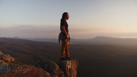 Long-haired rock climber finally reaches his destination at the top of the .. Stock Footage 264138300