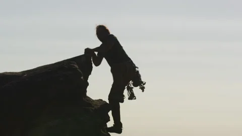 A Long-haired rock climber holding onto a rock and climbing Stock Footage 264138625