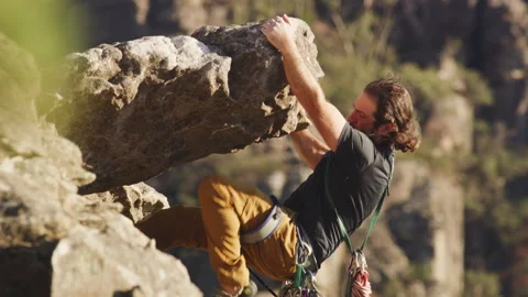 Long-haired rock climber holding onto a rock Stock Footage 264138937