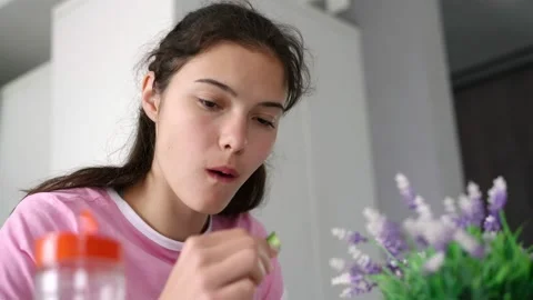 Long haired teenager eats cucumber and soup sitting at table Stock-Footage 134761920