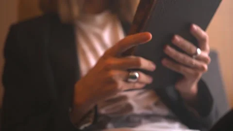 Long haired young man in black suit reads on windowsill aged book in black cover Stock Footage 198027071