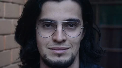 Long haired young man with glasses and beard looking at camera smiling Stock-Footage 211874645
