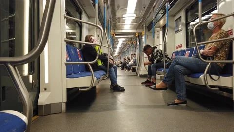 A long, half-empty subway car sways as it moves. Passengers wearing masks Video stock 137445004