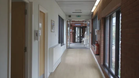 A long hallway with a brick wall and a white door Stock Footage 301622437