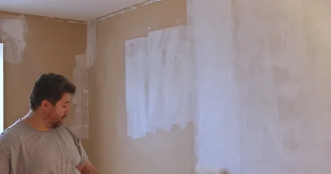 Long handle roller brush applying white primer paint on wall with home Vidéo 150609965