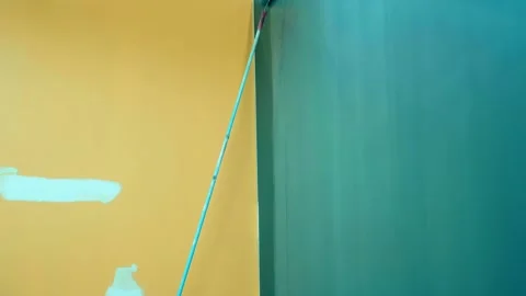 A long-handled roller is used to paint the high wall of the pavilion blue  Stock-Footage 333392225