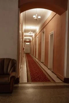 Long hotel corridor featuring a luxurious red carpet runner. Symmetrical Stock Photos