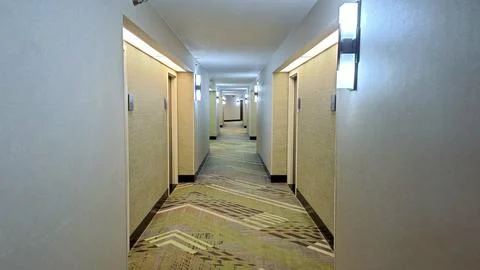 Long hotel hallway with patterned carpet and doors Stock Photos