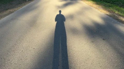 A long human shadow on an asphalt road in the rays  Stock-Footage 334068888