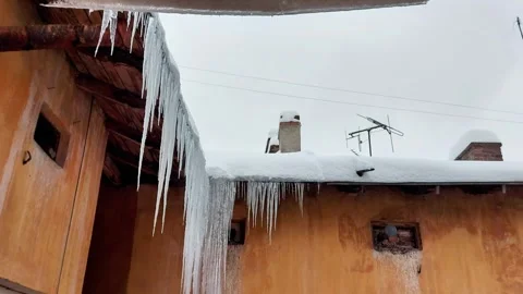 Long Icicles Hang from Snow - Covered Roof of Orange Urban Building Video stock 326317397