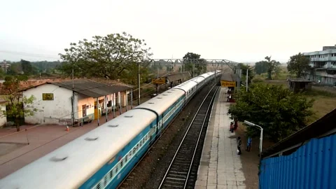 Long Indian Passenger express train crossing scenic Shelu railway station India Stock Footage 140214774