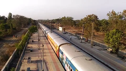 Long Indian Passenger express train crossing scenic Umroli railway station India Stock Footage 140639708