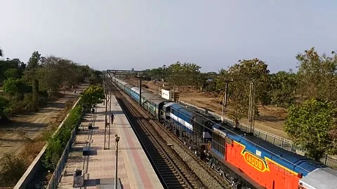 Long Indian Passenger express train crossing scenic Umroli railway station India Stock Footage 140642269