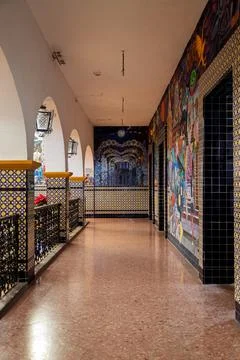 Long interior corridor of town hall with tiled columns, arches and vibrant mural Stock Photos