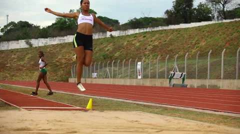 Track athlete landing in sand on long jump in super slow motion