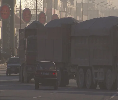 Long line of big coal trucks turning into smoggy traffic Stock Footage 86745765