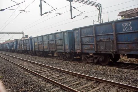 Long line of blue freight train wagons standing on railway tracks. Stock Photos