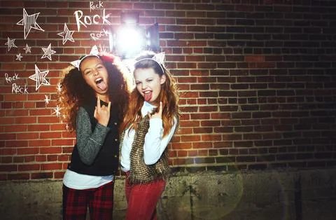 Long live Rock n Roll. two girls pulling faces and making a rock gesture. Stock Photos
