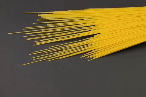 Long macaroni in a mug lies on a dark background Stock Photos