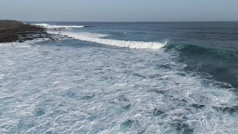 Long Ocean Waves Break into White Surf Beside Rocky Lanzarote Coastline Stock Footage 344023004