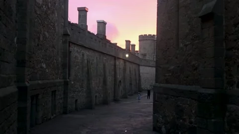 Long passageway with walls in an old castle with towers against a pink sunset Stock Footage 164654345