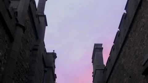 Long passageway with walls in an old castle with towers against a pink sunset Stock Footage 164654348