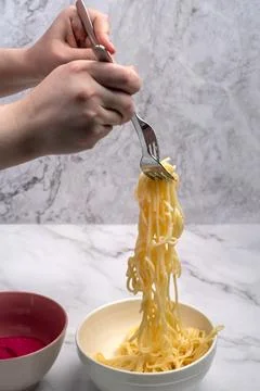 Long pasta or spaghetti on two forks in the hands of a young woman. Foto stock