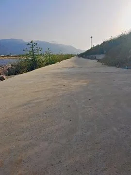 A long path made of cement, half shade and half sunlight on it Stock Photos