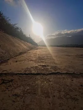 Long path by the river at sunset. The sky glows as the sun casts warm golden Stock-Fotos