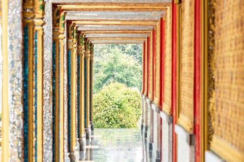 Long perspective corridor inside a Thai temple featuring golden frames, col.. Stock Photos