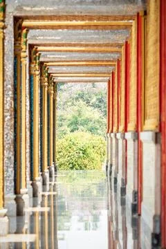 Long perspective corridor inside a Thai temple featuring golden frames, col.. 스톡 사진