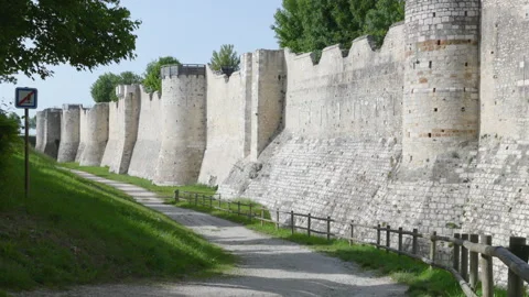 Long perspective of a medieval stone fortress wall with fortified towers and a d Stock Footage 336134192
