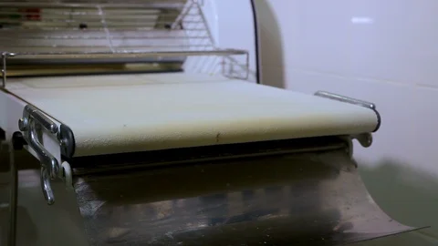 Long piece of dough on the rolling machine Stock Footage 106463724