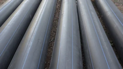 Long plastic black pipes of large diameter lie on the ground on the street Stock Footage 288436769