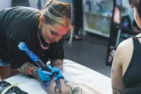 The long process of drawing a big leg tattoo. Indoor shot. Female tattooed Stock Photos