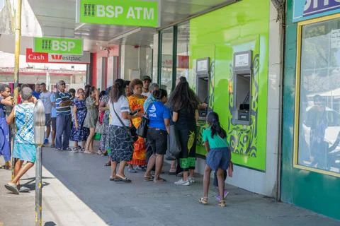 Long queue or line of people in street queuing outside ATM to get cash out. Stock Photos
