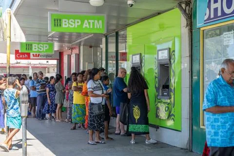 Long queue or line of people in street queuing outside ATM to get cash out. Stock Photos