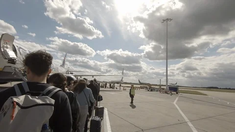 Long queue of passengers waiting with carry on luggage before boarding airplane Stock Footage 121136833