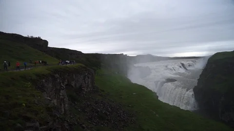 A long queue of tourists to Gullfoss Waterfall on Cloudy Day. Iceland. Slow Stock Footage 125582311