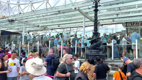 A long queue of visitors waiting to board the London Eye Stock Footage 327645474
