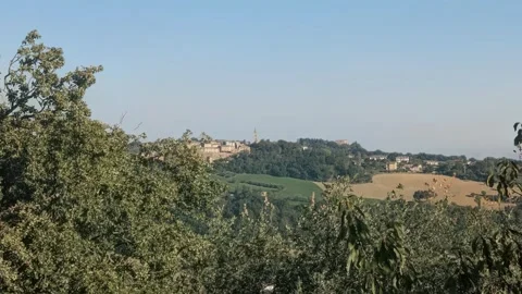 Long-range panoramic view of a hilltop village nestled Vídeos de archivo 346695568