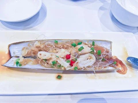 A long razor clam shell serves as a dish for steamed seafood, vermicelli glass n Stock Photos