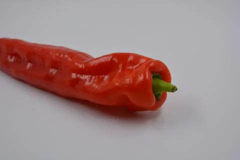 A long red bell pepper with a green tail is on white background. Stock Photos