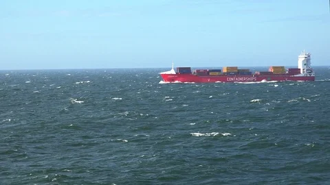 Long red cargo ship with coloured containers sails on sea Stock Footage 114262785