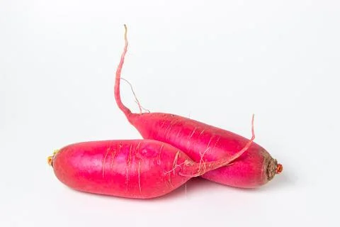 Long red radish on a white background. Delicious and healthy vegetables. Stock Photos